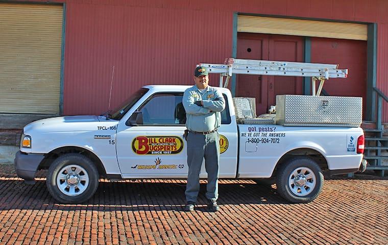 a pest control technician and company truck in front of a commercial building in silsbee texas