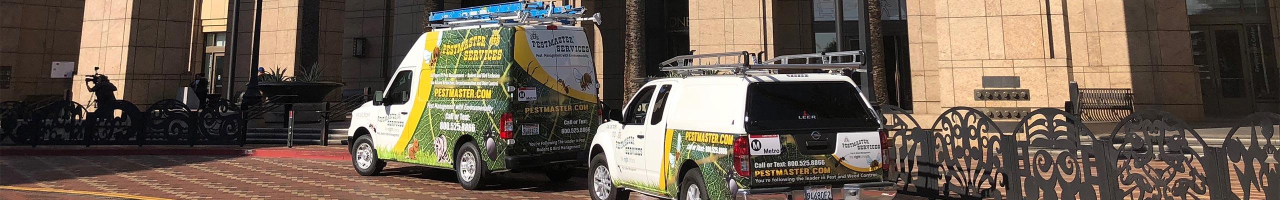 two pest control service vehicles parked outside of a commercial building