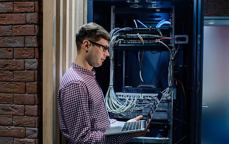 man looking at a laptop in a server room