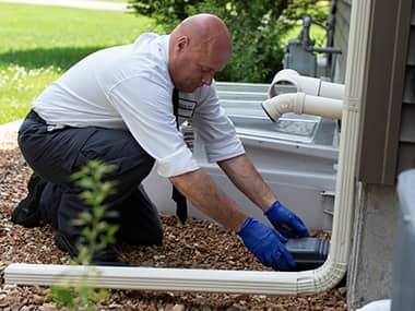 Mice Leave Droppings & Chew Holes Behind a technician setting up a rodent trap outside a home in peoria illinois
