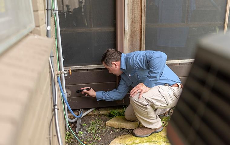 a pest technician inspecting the exterior of a home for termites in modesto california