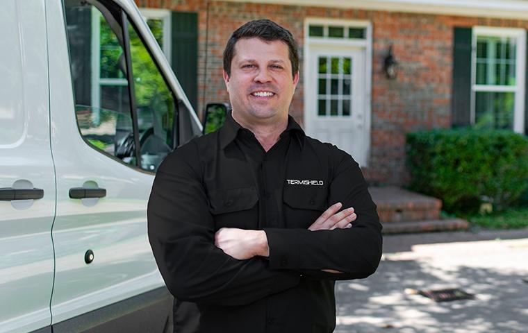 a pest control service technician posing outside of a home in hammond indiana