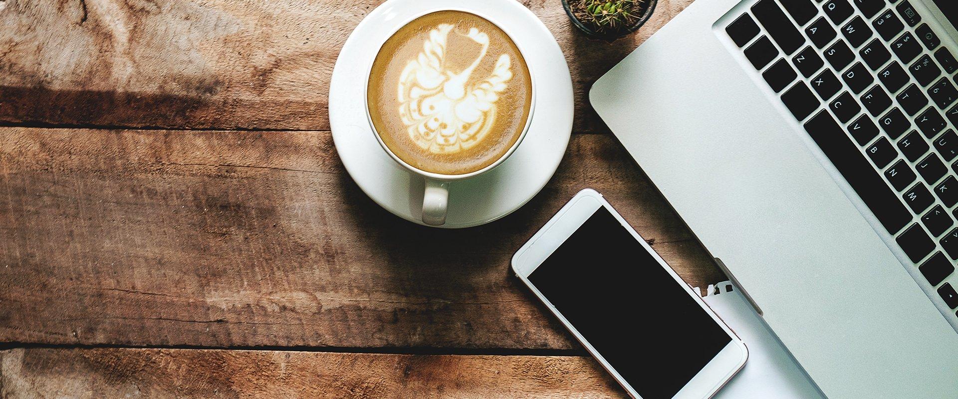 coffee, a smartphone, and a laptop on a table