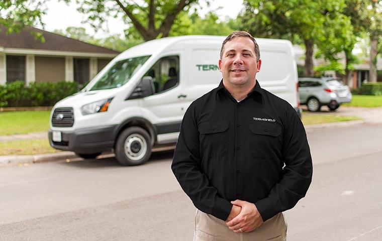 a pest control service technician posing in front of a company vehicle outside of a home in mishawaka indiana