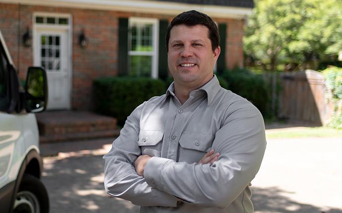 pest-pro services technician standing outside a longview texas home