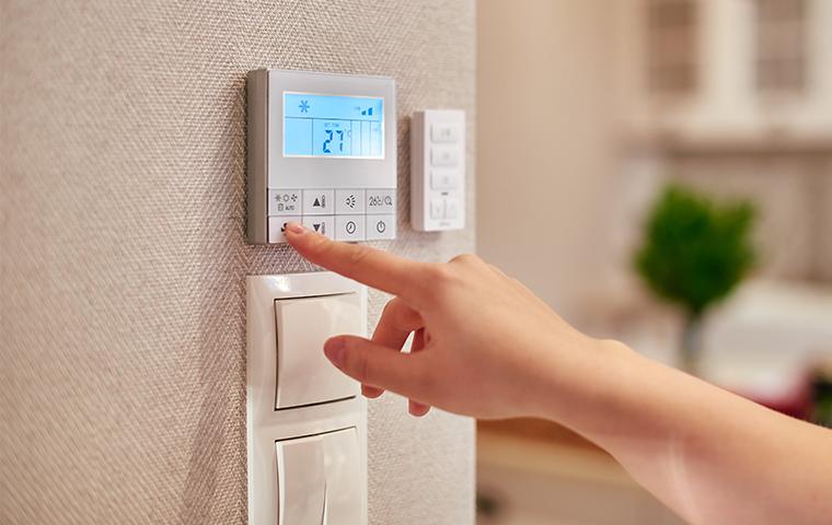person pressing button on thermostat