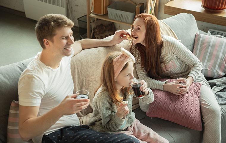 couple eating pizza on couch with daughter