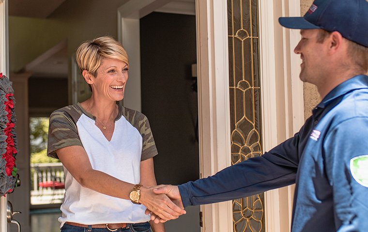 a pest control expert shaking hands with a customer