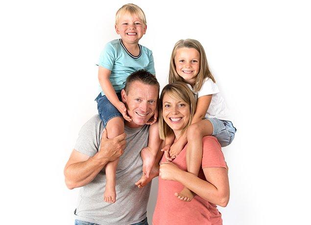 two parents with smiling children sitting on their shoulders