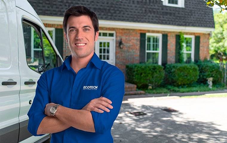 smiling technician near vehicle and brick home