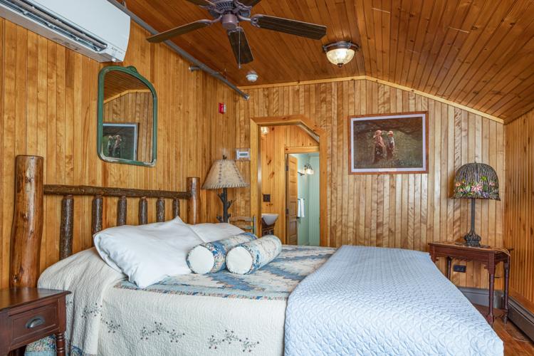 A bed, mirror, lamp, and ceiling fan in a wood paneled room