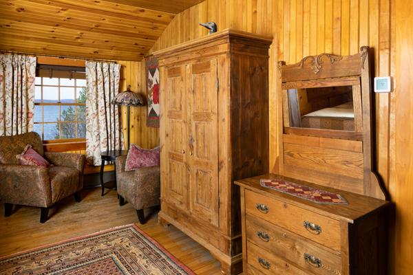Two chairs, a dresser, and an armoire in a wood paneled room