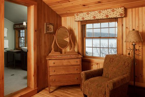 A dresser, chair, and mirror in a wood paneled room