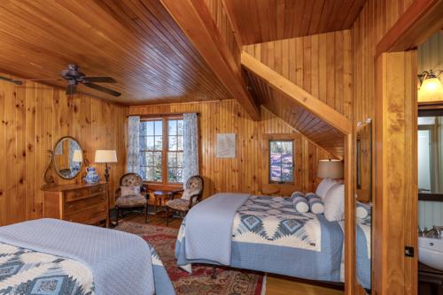 Two beds, two chairs, a dresser, and a mirror in a wood paneled room
