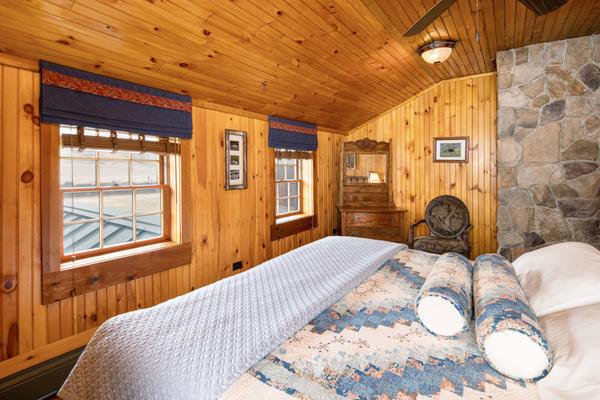 A bed, chair, dresser, and mirror in a wood paneled room