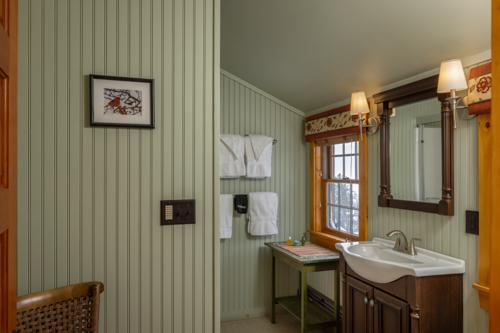 A bathroom with a sink, and green and white striped wallpaper