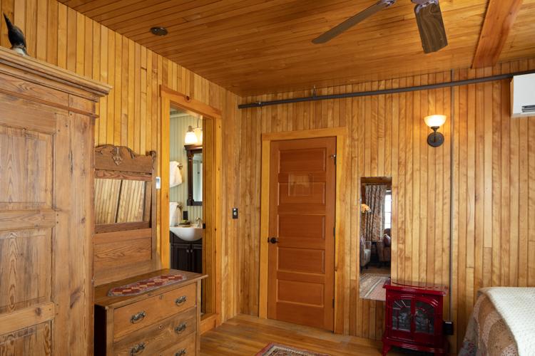 A dresser, a wood stove, and a red door in a wood paneled room