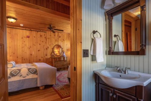 A bathroom sink and a mirror to the right and a bed to the left in a wood paneled room