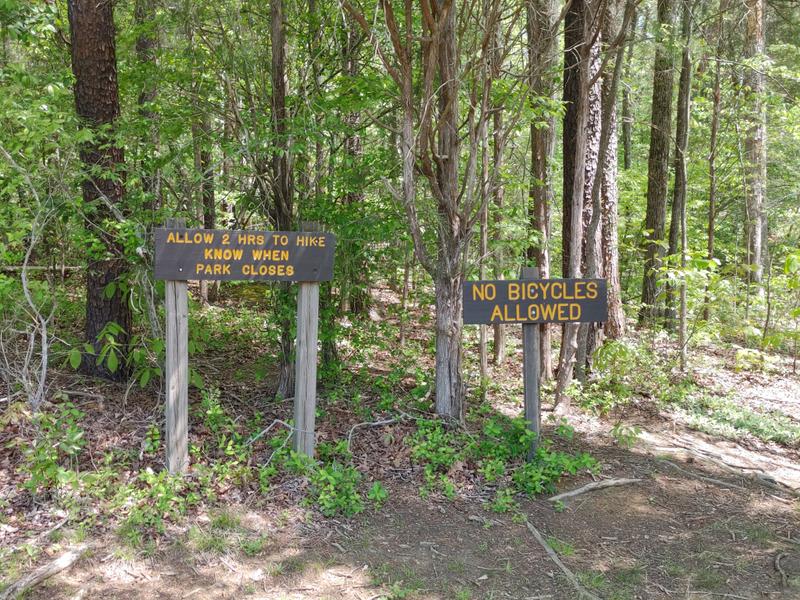 The 2 mile loop was hard to find.  You can find the entrance by these signs which are off the trail around the lake. When you see these signs, go past them and walk across the field. Here you will find the trailhead. (Credit: David Morway)