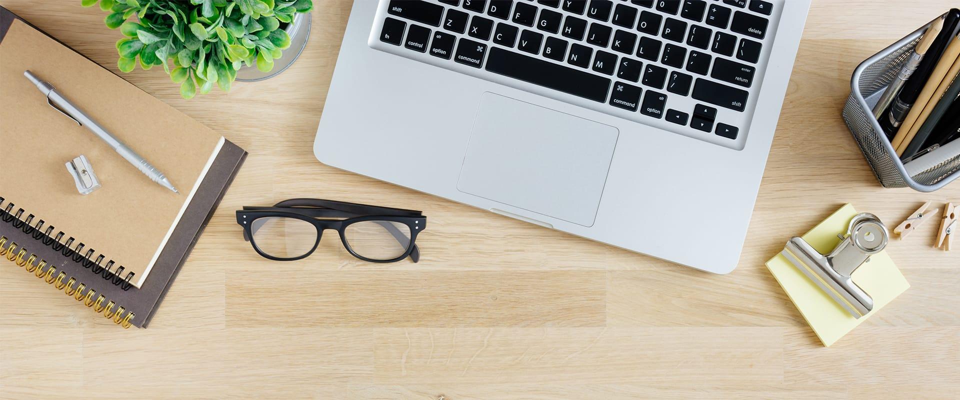wooden desk with notebooks pencil glasses laptop and office supplies