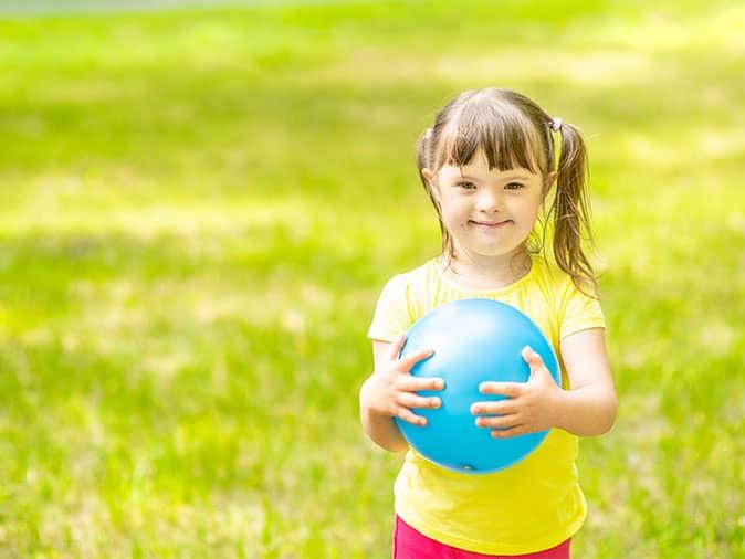 little girl with down syndrome playing with ball