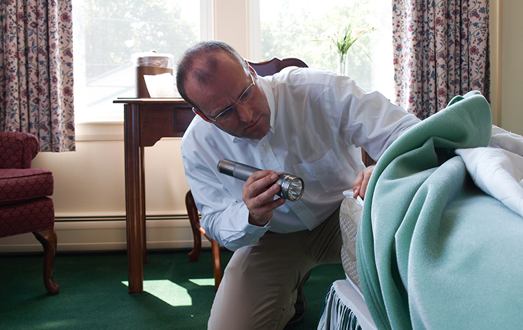 There Are Many Ways That Bed Bugs Invade Your Home a holifield pest management service technician inspecting for bed bugs in a montrose mississipi home