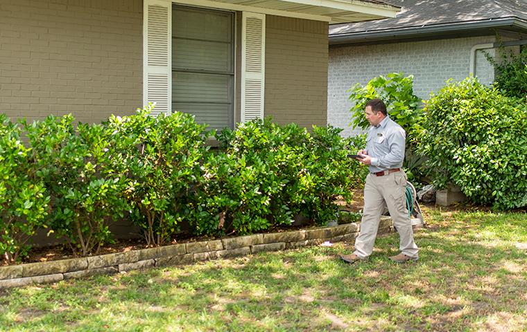 Our Year-Round Pest Control Is Extremely Effective a pest technician performing an exterior inspection at a home in castaic california