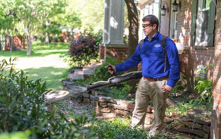 Enjoy Your Yard Again With Our Mosquito Control a service technician performing a mosquito treatment outside a home in aiken south carolina