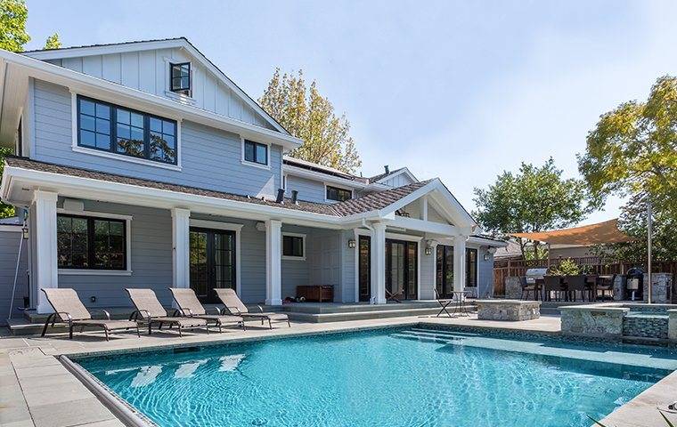 a white two story house with a pool in back