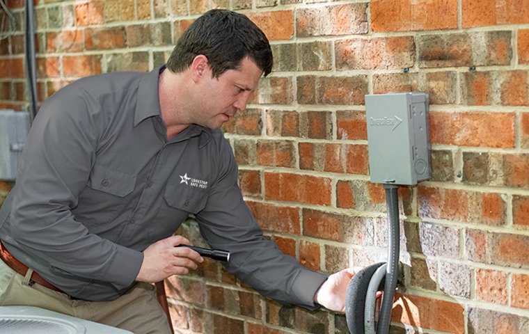 a pest control service technician inspecting the perimeter of a home for pests