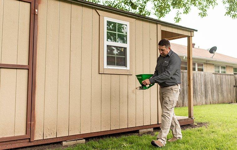 a pest control service technician inspecting the exterior of a home for pests