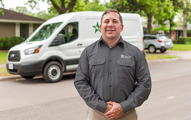 a pest control service technician standing outside of a home