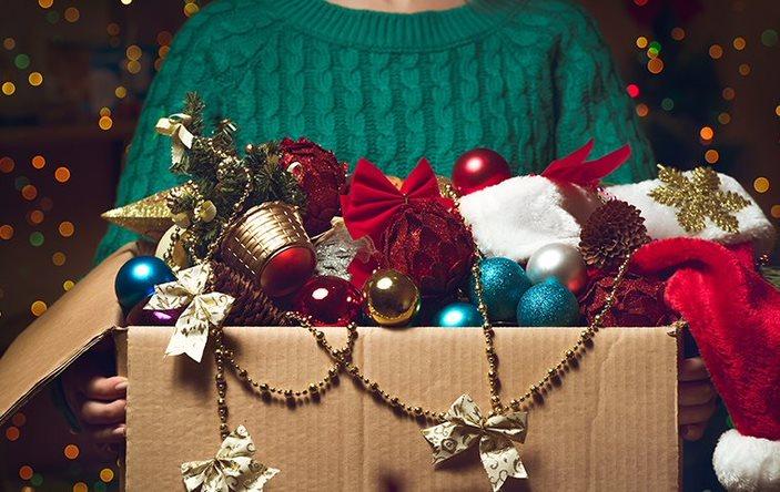 A woman holding a box of Christmas decorations.