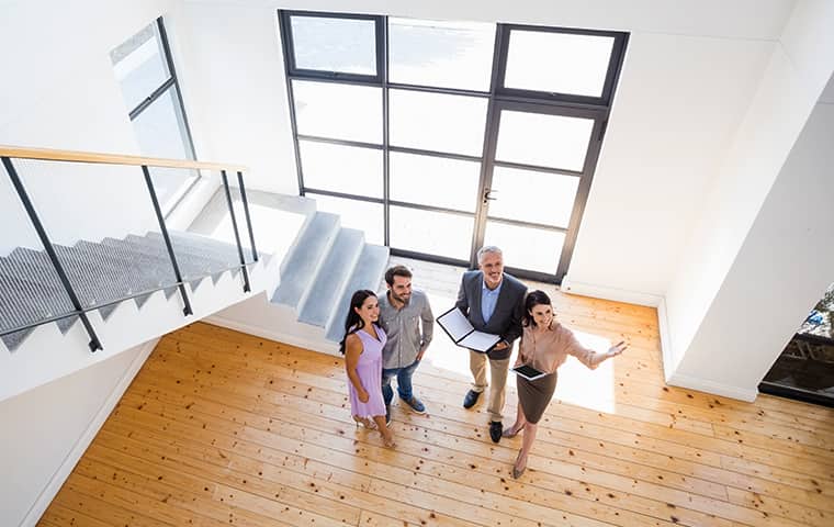 a real estate agent and two hopeful homeowners inside of a property for sale serviced by addison pest control of texas in frisco