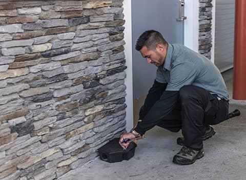 Protect Your Wilton NY Business With Thomas Pest Services technician checking rodent station in wilton