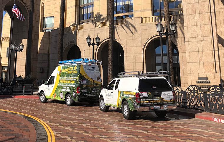 two pestmaster services vehicles parked in front of a commercial building