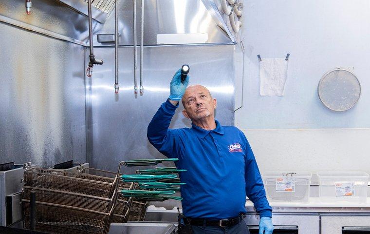 a pest technician inspecting a bryceville florida commercial kitchen