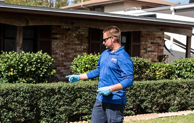 a technician standing in front of and inspecting a palatka florida home for pests