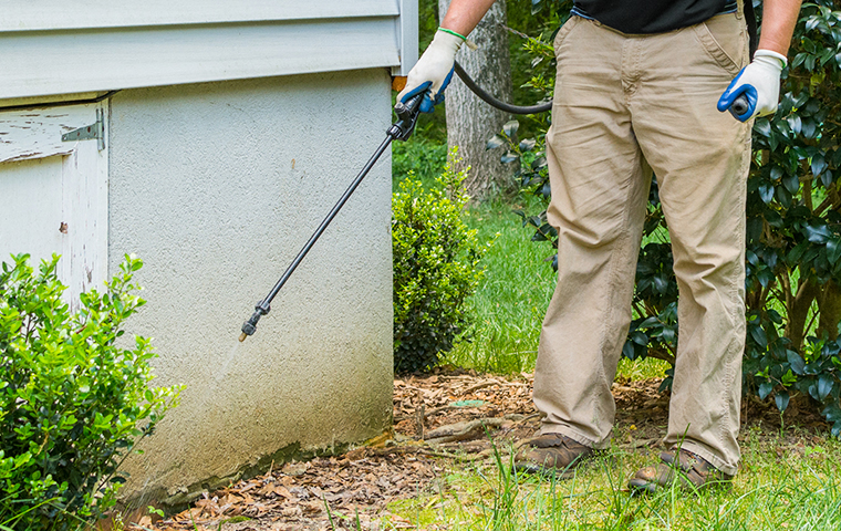Our Pest Treatments Produce Results a technician performing a spray treatment outside a home in garrison
