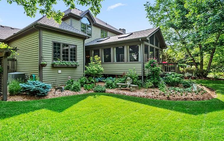 backyard view of a house with a beautiful green lawn and landscaping