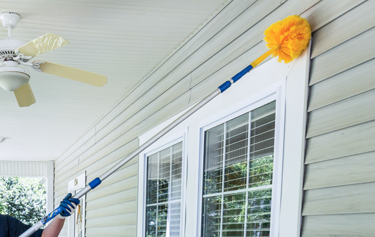 Our Pest Treatments Are Effective a technician dewebbing the doorway of a home in houston texas