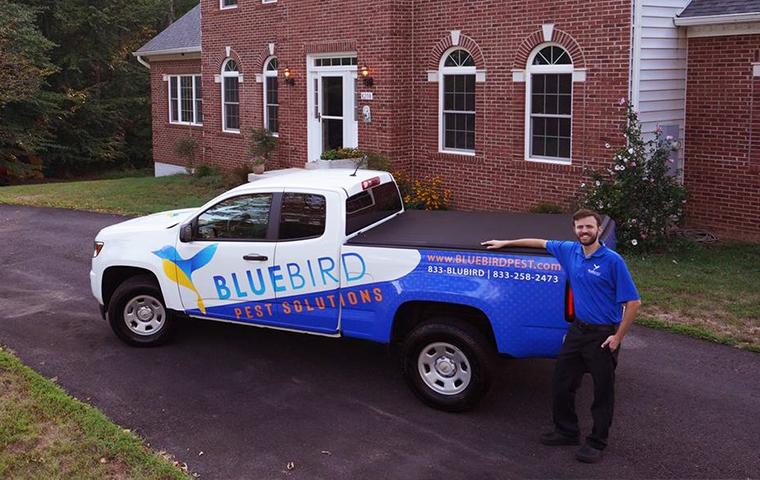 blue bird technician in front of truck and house