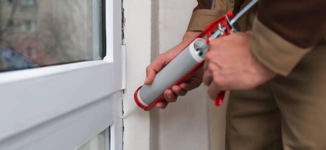 homeowner sealing cracks to prevent spiders