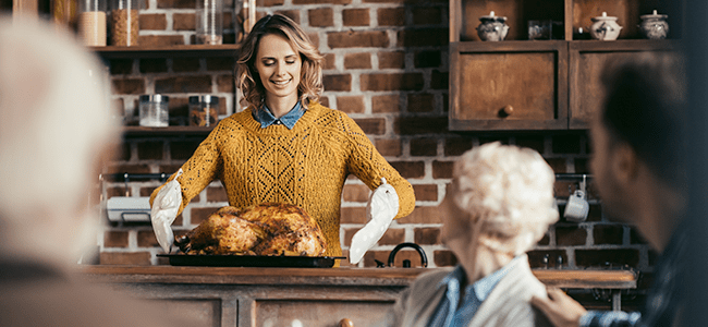 a middle aged woman prepares to carry a cooked turkey to the dinner table for her guests
