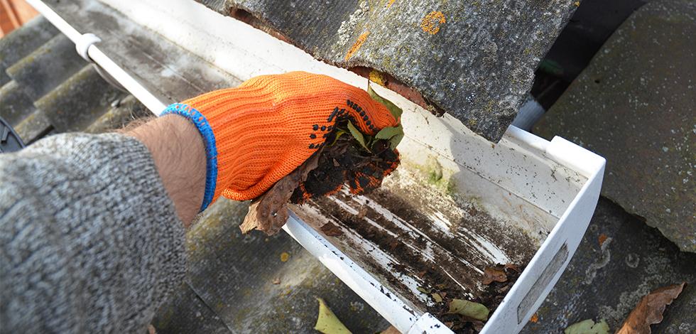 a person cleaning out a gutter in virginia