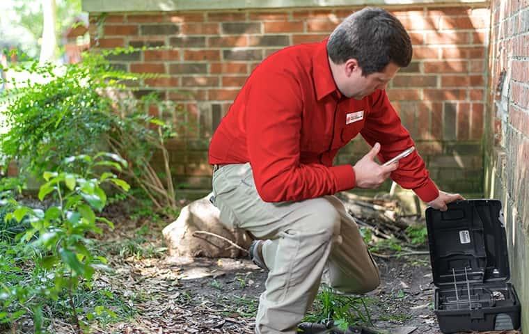Call Today a pest control service technician applying pest control treatments to the exterior of a home in murrieta california