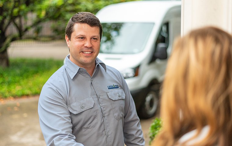 a pest technician greeting a customer in front of her home in washington dc