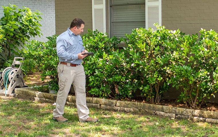 Our Residential Pest Control a pest technician inspecting the exterior of a home in washington dc