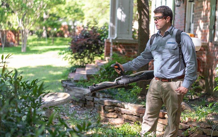 a pest technician treating the exterior of a home for mosquitoes in washington dc