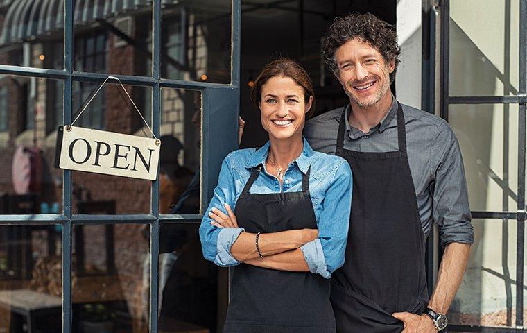 relieved business owners next to the open sign